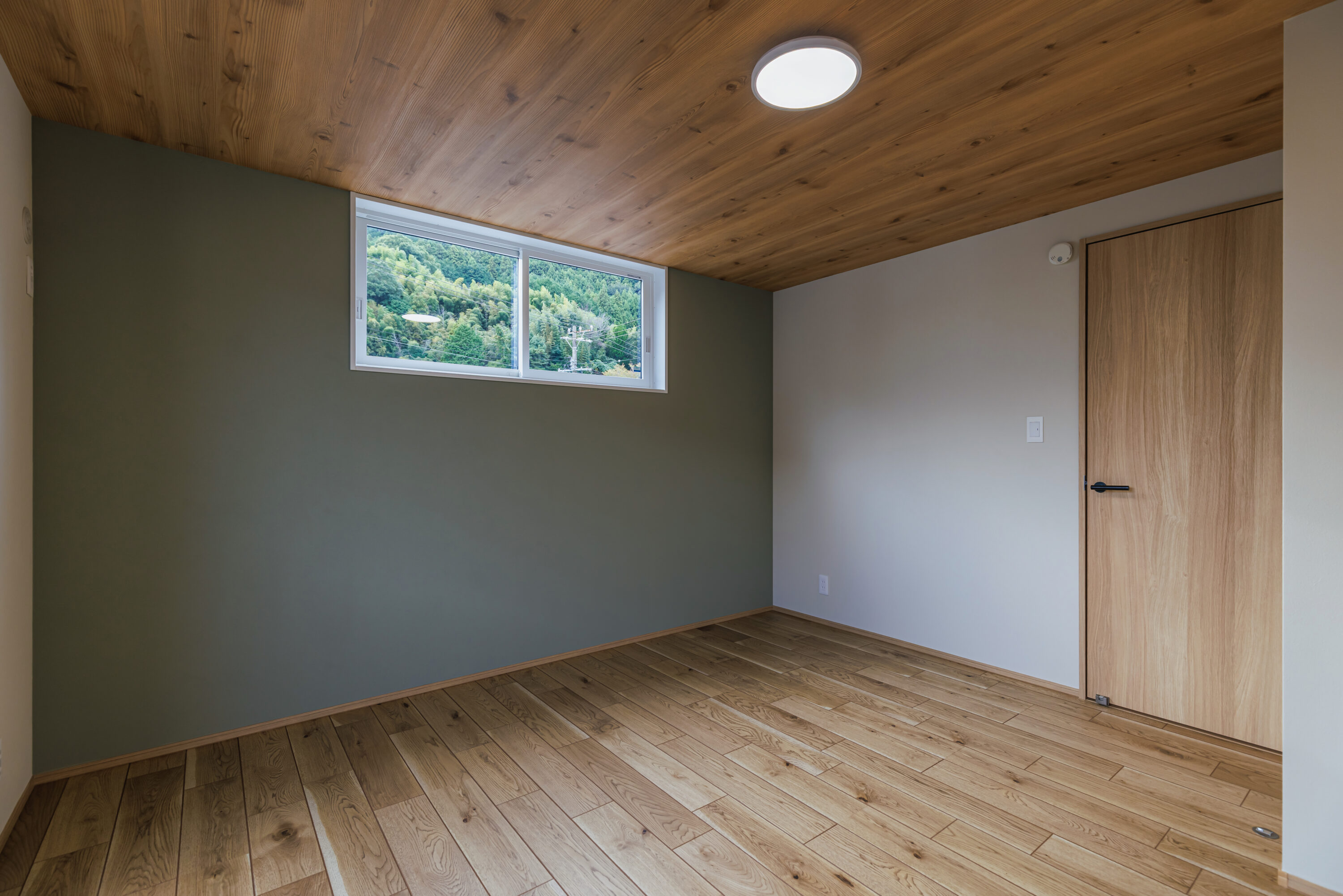 モスグリーンの外壁と木が調和する、静かな佇まいの家の写真24