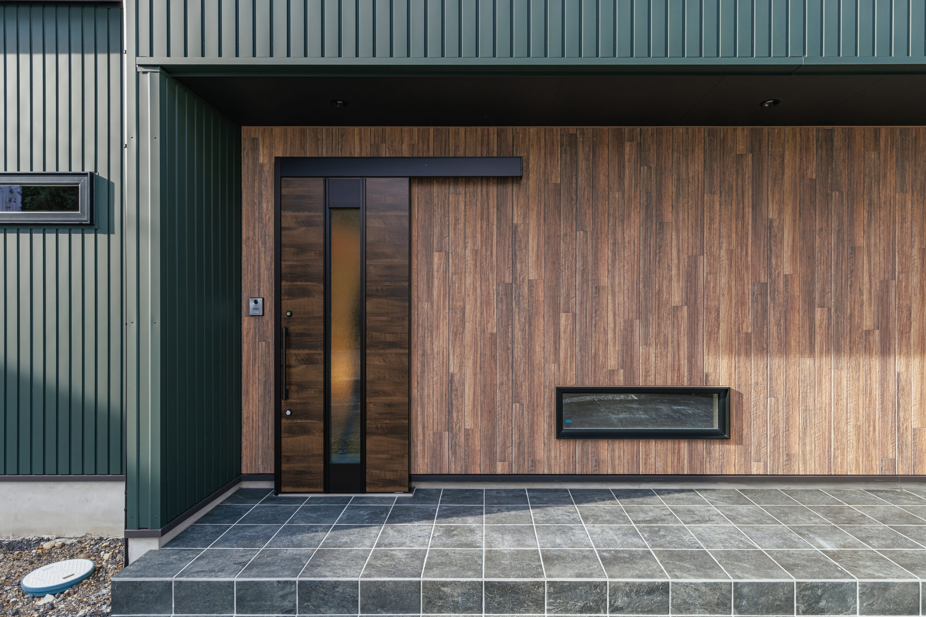 モスグリーンの外壁と木が調和する、静かな佇まいの家の写真25