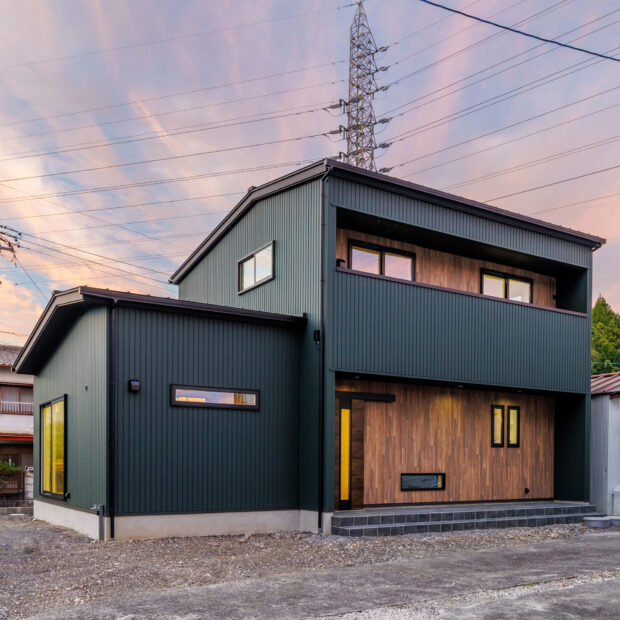 モスグリーンの外壁と木が調和する、静かな佇まいの家