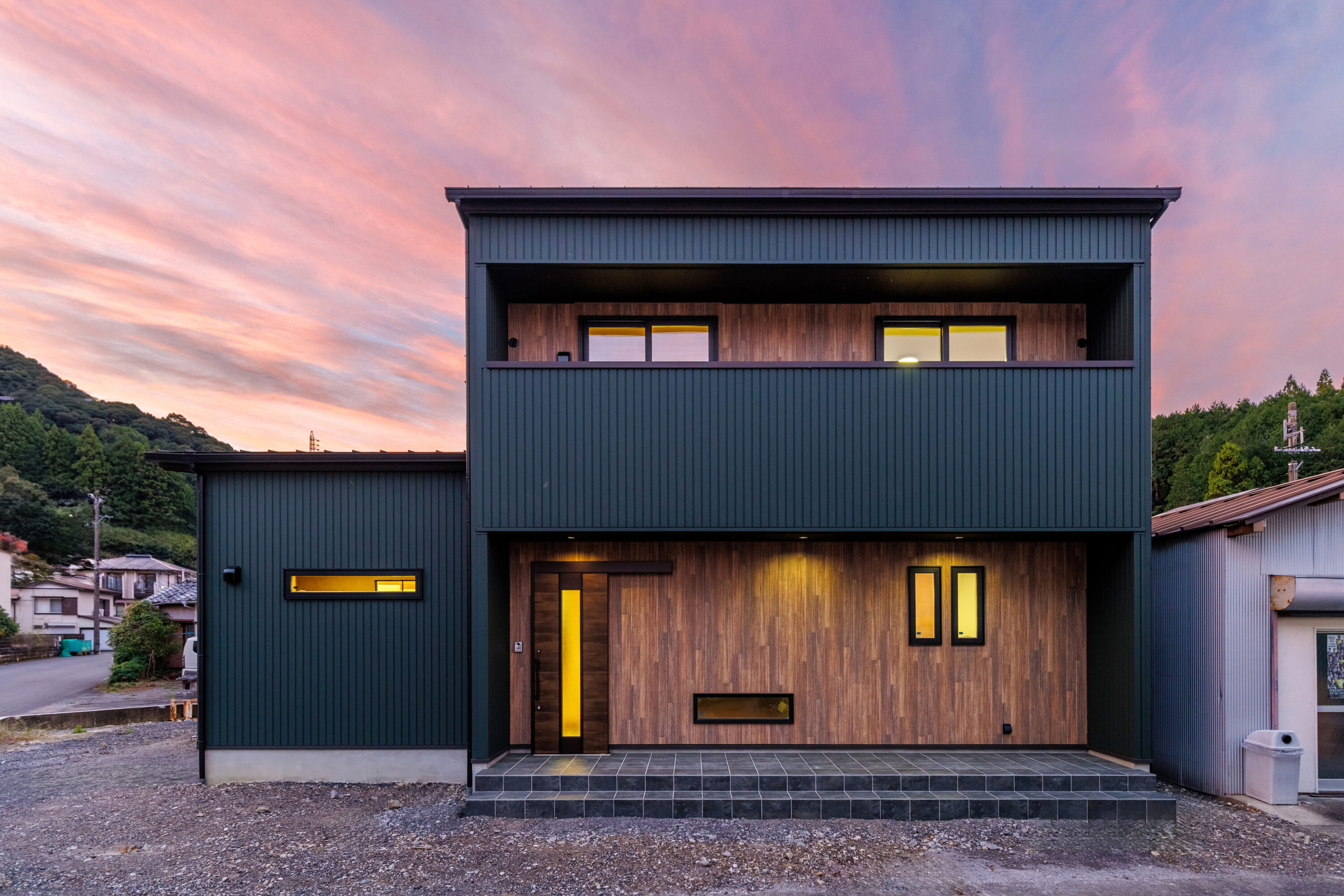 モスグリーンの外壁と木が調和する、静かな佇まいの家の写真1